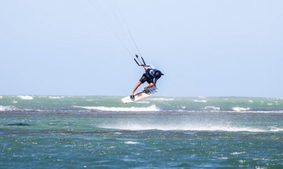Dynamic kitesurfing action over ocean waves in Adicora, capturing the thrill of summer water sports.